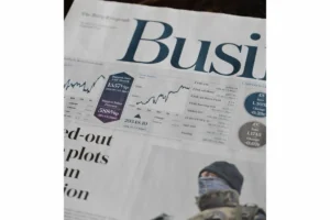 Um jornal com um gráfico ao fundo do mercado financeiro Source: Unsplash